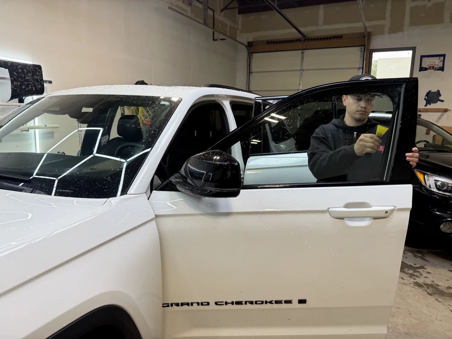 ACS technician installing ceramic window tint on a Jeep Grand Cherokee